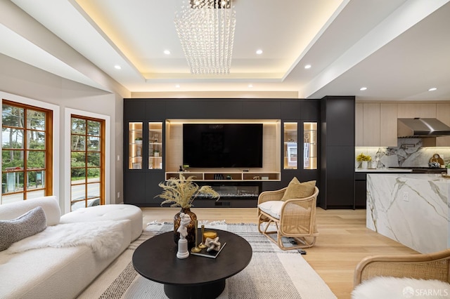 living area with a chandelier, light wood-style floors, a raised ceiling, and recessed lighting