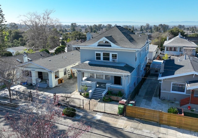 view of front facade featuring driveway, a fenced front yard, roof with shingles, covered porch, and a gate