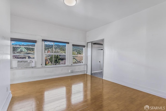 empty room featuring cooling unit, baseboards, and wood finished floors