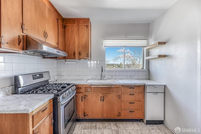 kitchen with tasteful backsplash, stainless steel gas range, light countertops, under cabinet range hood, and a sink