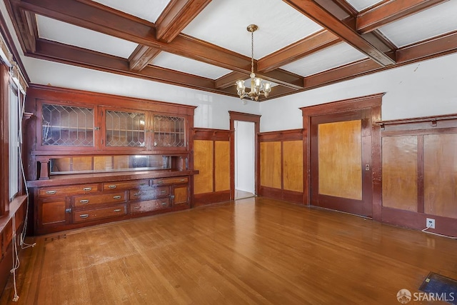 unfurnished living room featuring a chandelier, beamed ceiling, coffered ceiling, and wood finished floors