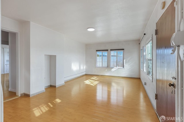 unfurnished room featuring a baseboard radiator, light wood-style flooring, and baseboards