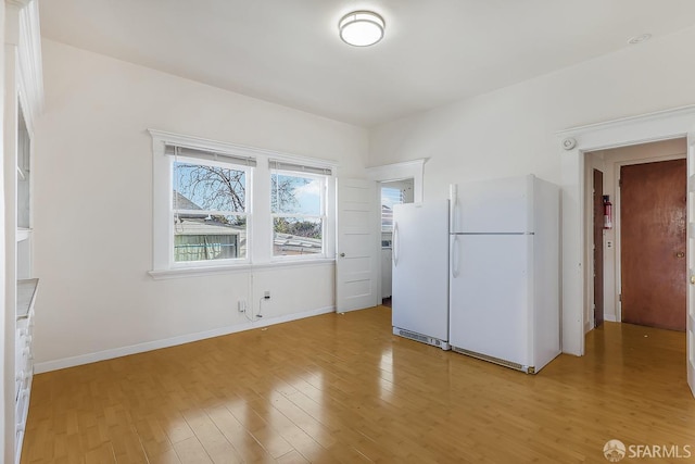 interior space featuring freestanding refrigerator, baseboards, and light wood finished floors