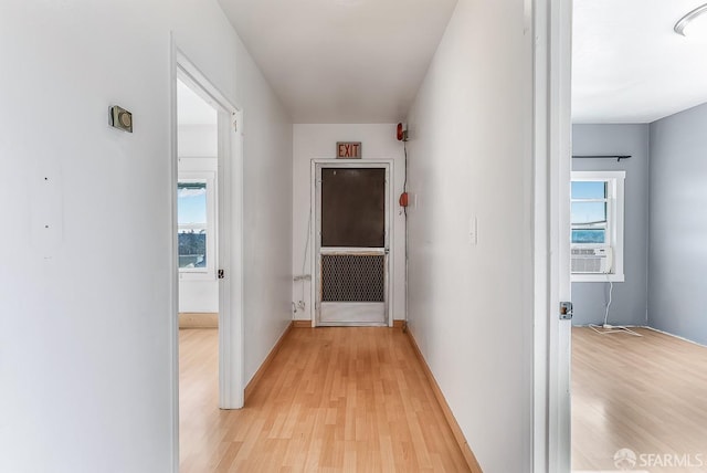 hallway featuring light wood finished floors and baseboards