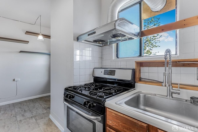 kitchen featuring decorative backsplash, a sink, island range hood, stainless steel gas range oven, and baseboards