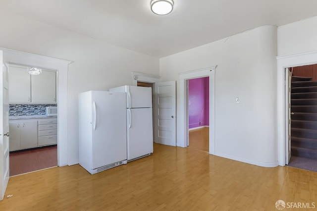 kitchen featuring white appliances, tasteful backsplash, baseboards, light countertops, and light wood-style floors