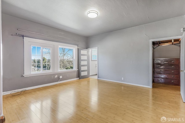 spare room featuring a textured ceiling, baseboards, and wood finished floors