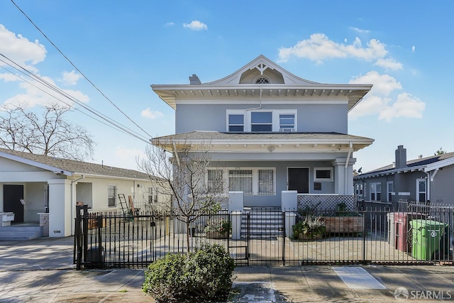 american foursquare style home with a fenced front yard, a porch, and stucco siding