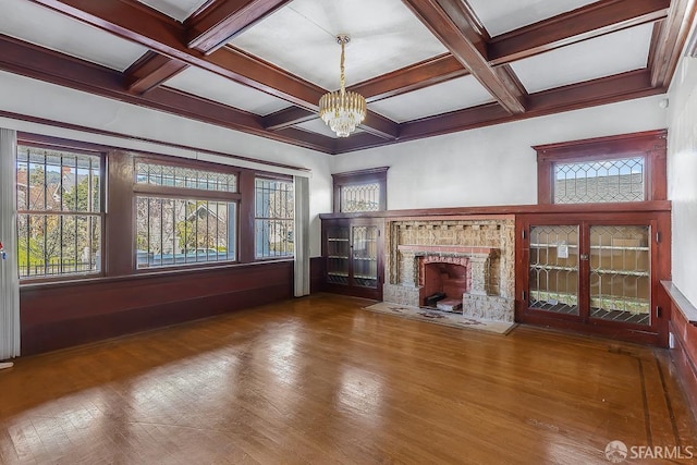 unfurnished living room featuring a chandelier, a fireplace, coffered ceiling, and beam ceiling