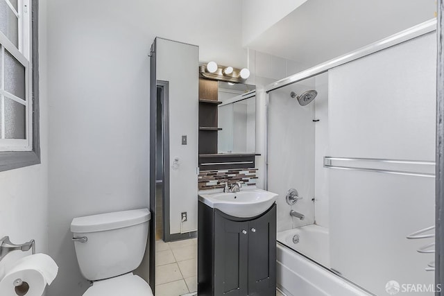 bathroom featuring toilet, bath / shower combo with glass door, vanity, backsplash, and tile patterned floors