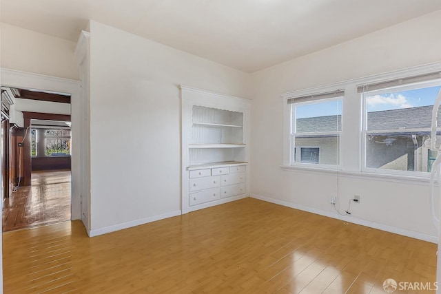 empty room featuring light wood-type flooring and baseboards