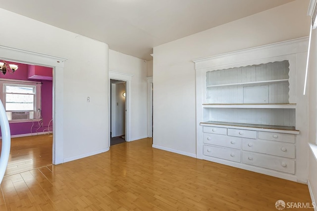 interior space with light wood-type flooring, baseboards, cooling unit, and a notable chandelier