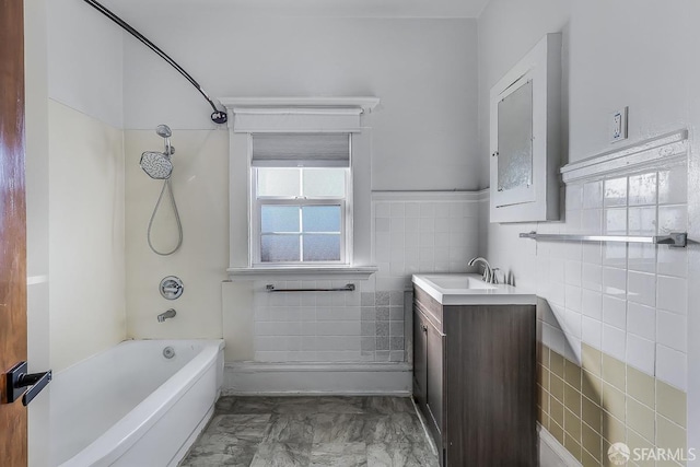 bathroom featuring washtub / shower combination, marble finish floor, vanity, and tile walls