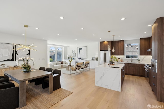 26 Southwood Dr, San Francisco, CA 94112 - kitchen featuring modern cabinets, stainless steel refrigerator, open floor plan, a center island with sink, and recessed lighting