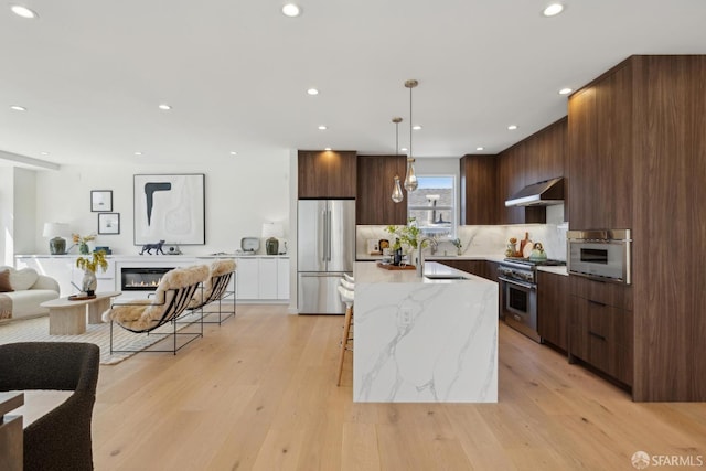 26 Southwood Dr, San Francisco, CA 94112 - kitchen with appliances with stainless steel finishes, modern cabinets, under cabinet range hood, a sink, and a center island with sink