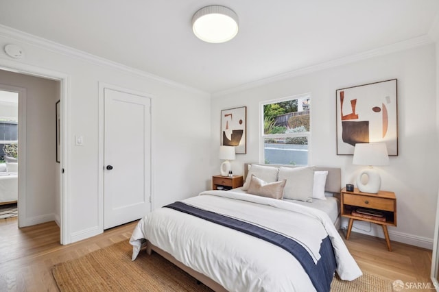 bedroom featuring ornamental molding and light hardwood / wood-style floors