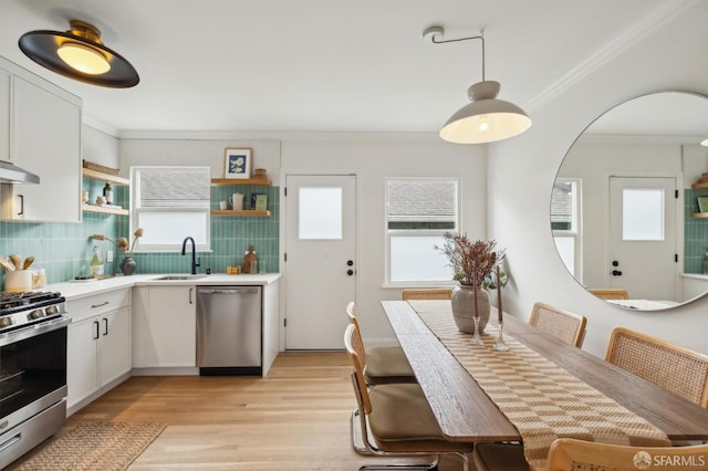 kitchen featuring appliances with stainless steel finishes, white cabinetry, sink, decorative backsplash, and crown molding