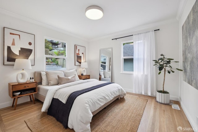 bedroom with multiple windows, ornamental molding, and light hardwood / wood-style flooring