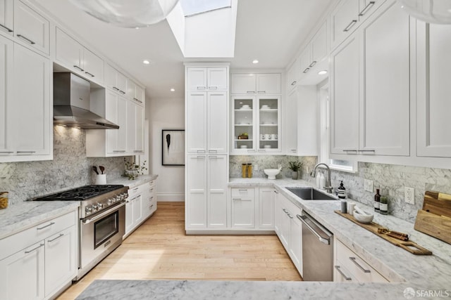 267 Bonview St, San Francisco, CA 94110 - kitchen with appliances with stainless steel finishes, wall chimney exhaust hood, white cabinetry, light stone countertops, and recessed lighting