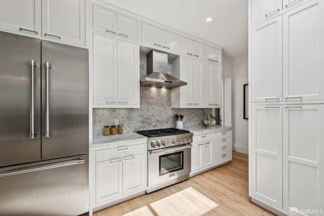 267 Bonview St, San Francisco, CA 94110 - kitchen featuring high quality appliances, wall chimney range hood, decorative backsplash, white cabinets, and recessed lighting