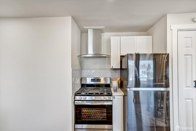 kitchen featuring tasteful backsplash, white cabinetry, wall chimney exhaust hood, and appliances with stainless steel finishes