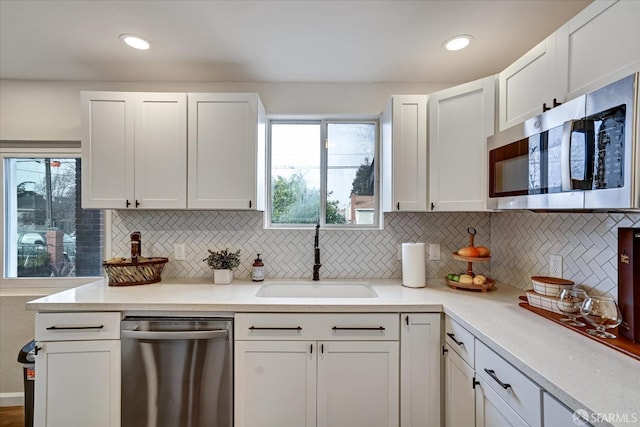 kitchen featuring white cabinets, decorative backsplash, stainless steel appliances, and sink