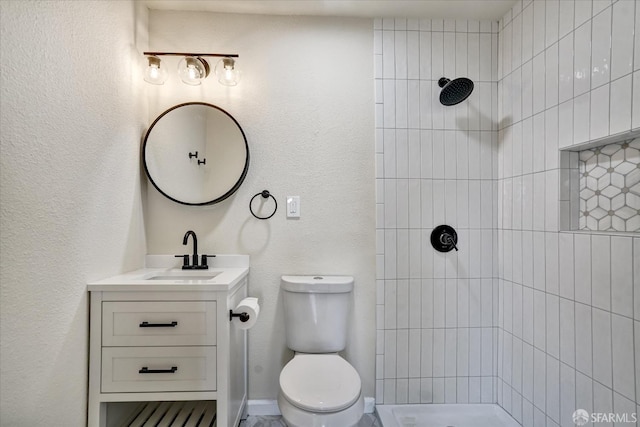 bathroom with vanity, toilet, and a tile shower