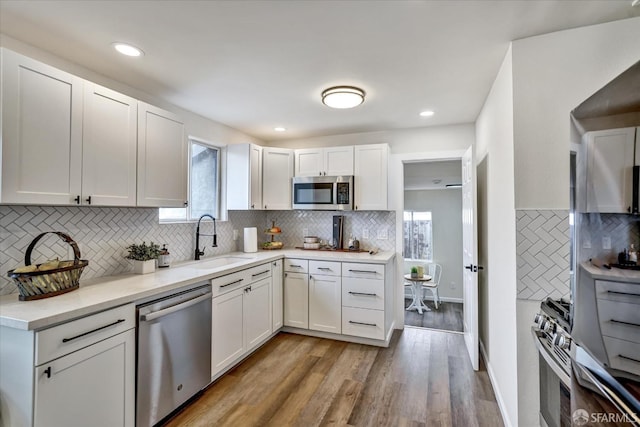 kitchen featuring sink, tasteful backsplash, light hardwood / wood-style floors, white cabinetry, and stainless steel appliances