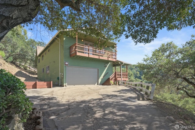 view of front facade featuring a garage, a balcony, and driveway