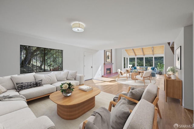 living area featuring a fireplace, light wood-type flooring, and vaulted ceiling