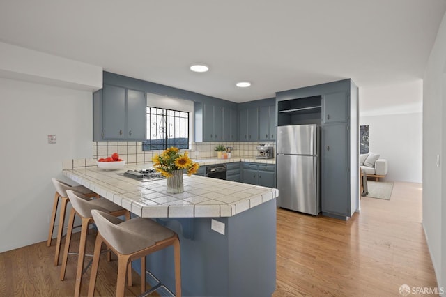 kitchen with backsplash, a kitchen bar, a peninsula, freestanding refrigerator, and open shelves