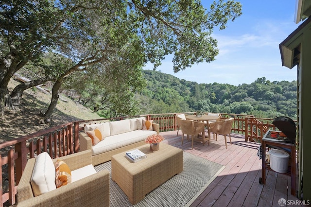 wooden terrace with outdoor dining space, outdoor lounge area, and a wooded view