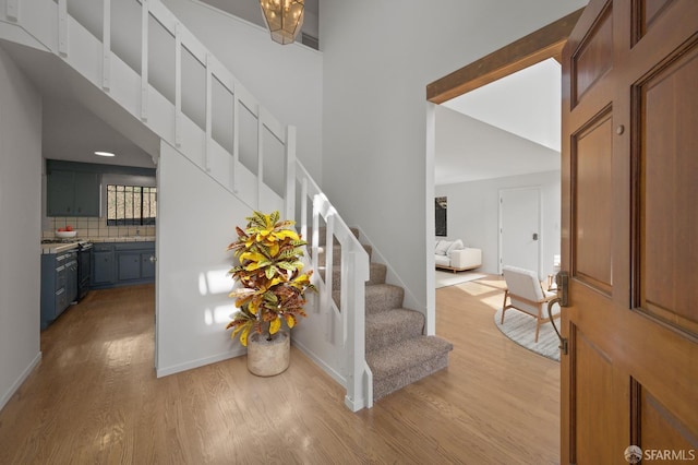 entryway with stairway, a high ceiling, light wood-type flooring, and baseboards