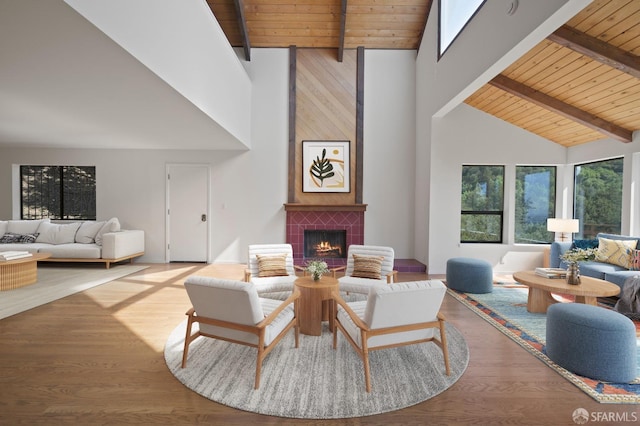 living area with beamed ceiling, wood finished floors, wooden ceiling, and a tiled fireplace