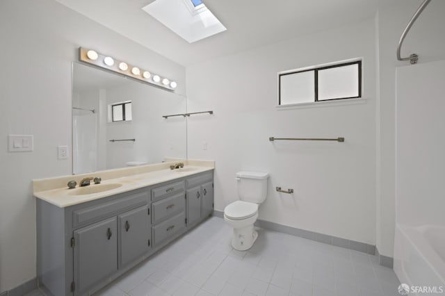 bathroom featuring baseboards, double vanity, a skylight, a sink, and toilet