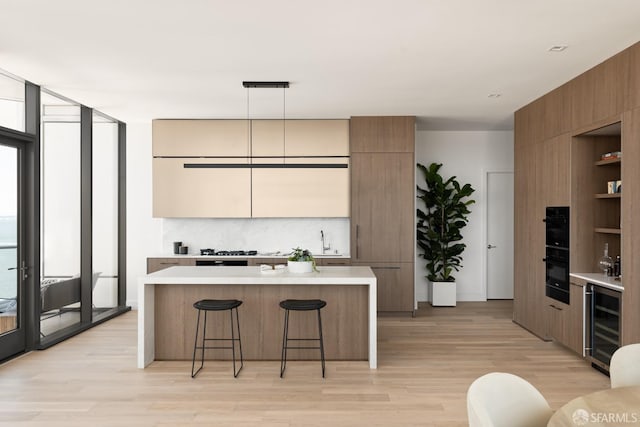 kitchen featuring expansive windows, a kitchen island, hanging light fixtures, and beverage cooler