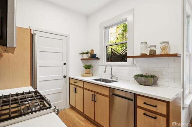 kitchen with decorative backsplash, sink, stainless steel dishwasher, and light hardwood / wood-style flooring