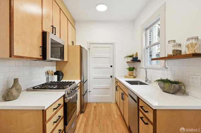 kitchen with decorative backsplash, appliances with stainless steel finishes, light wood-type flooring, and sink