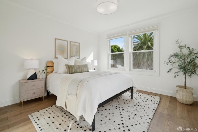 bedroom featuring light wood-style floors, baseboards, and crown molding