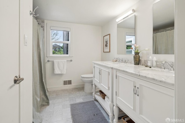 full bath with visible vents, a sink, toilet, and double vanity