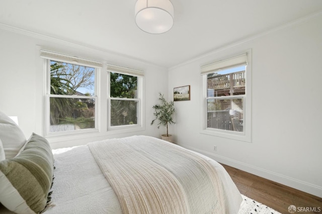 bedroom featuring crown molding, baseboards, and wood finished floors