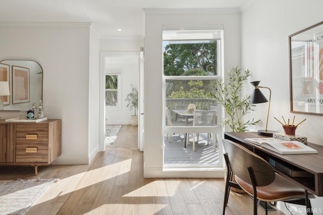 home office featuring light wood-style floors, ornamental molding, and baseboards