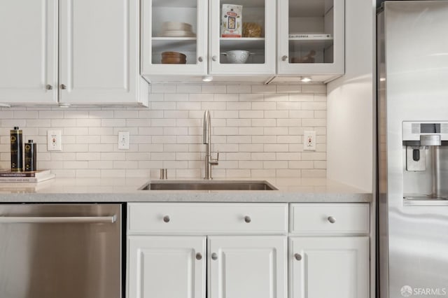 kitchen featuring appliances with stainless steel finishes, a sink, glass insert cabinets, and white cabinets