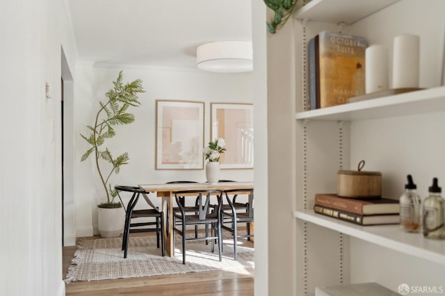 dining room featuring crown molding, baseboards, and wood finished floors