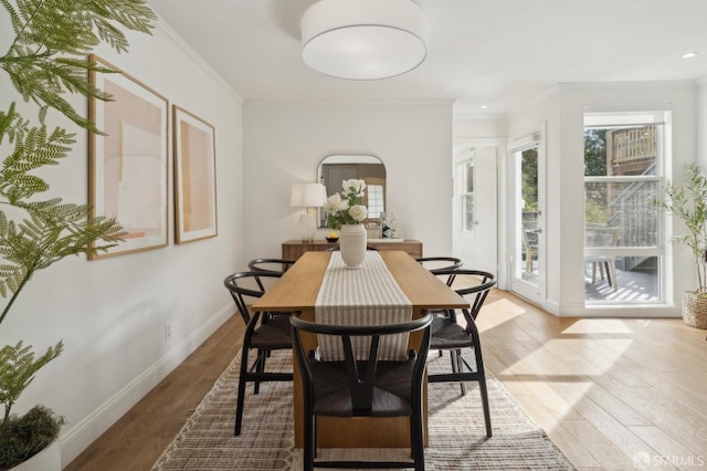 dining space with light wood-style floors, crown molding, and baseboards