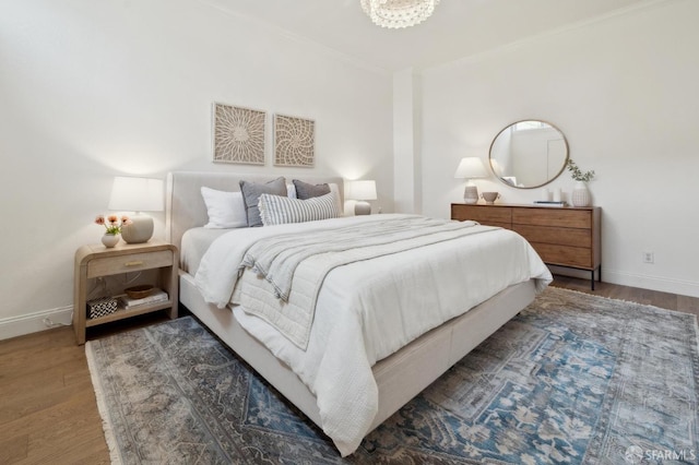 bedroom with baseboards, ornamental molding, and wood finished floors