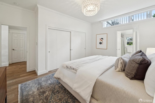 bedroom with ornamental molding, a closet, wood finished floors, and an inviting chandelier