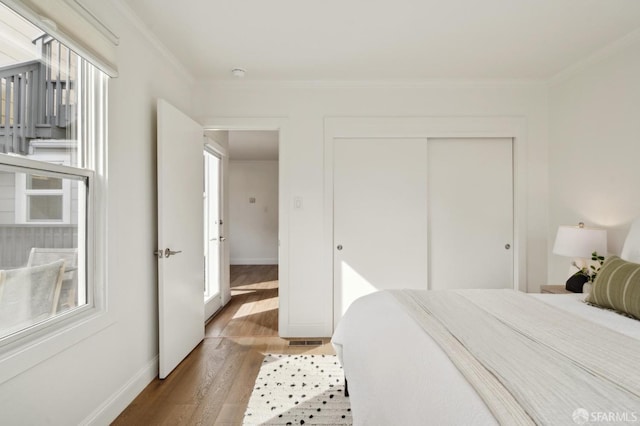 bedroom with ornamental molding, a closet, baseboards, and light wood finished floors