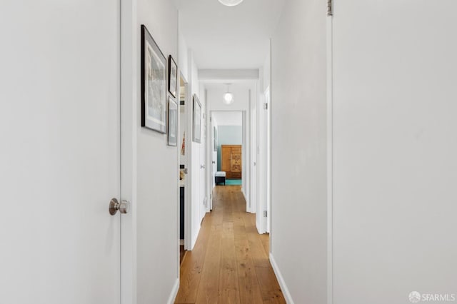 corridor with light wood-type flooring and baseboards