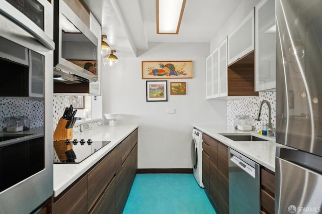 kitchen featuring appliances with stainless steel finishes, a sink, washer / dryer, light countertops, and modern cabinets